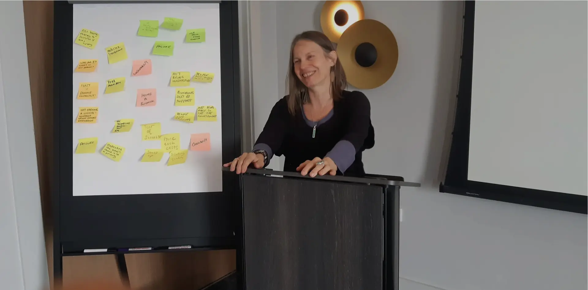 Nicky Torode speaking beside a flipchart covered in participants' notes